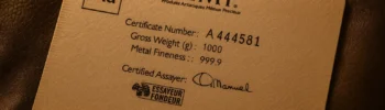 Close-up of a PAMP Suisse gold bar assay certificate showing serial number, fineness, and certified assayer signature.