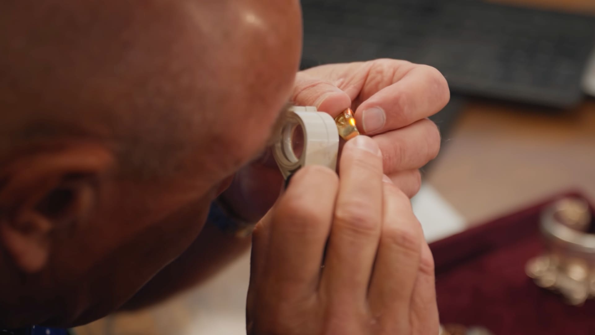 Expert examining a gold coin ring under a jeweler's loupe for grading and evaluation
